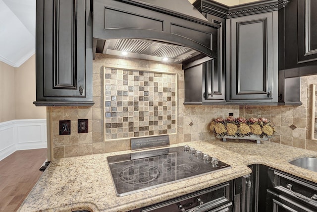 kitchen featuring oven, wood finished floors, dark cabinetry, black electric stovetop, and custom range hood
