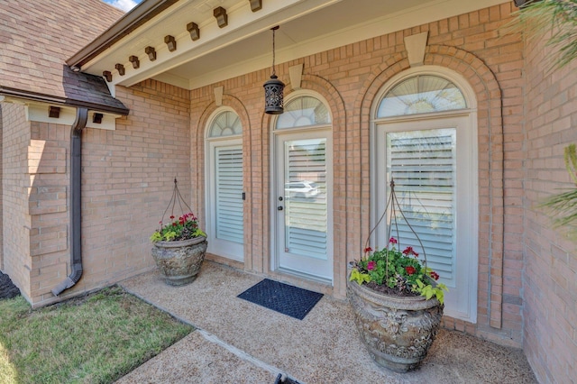 entrance to property with brick siding and roof with shingles