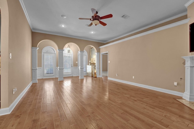 unfurnished living room with a ceiling fan, crown molding, arched walkways, visible vents, and decorative columns