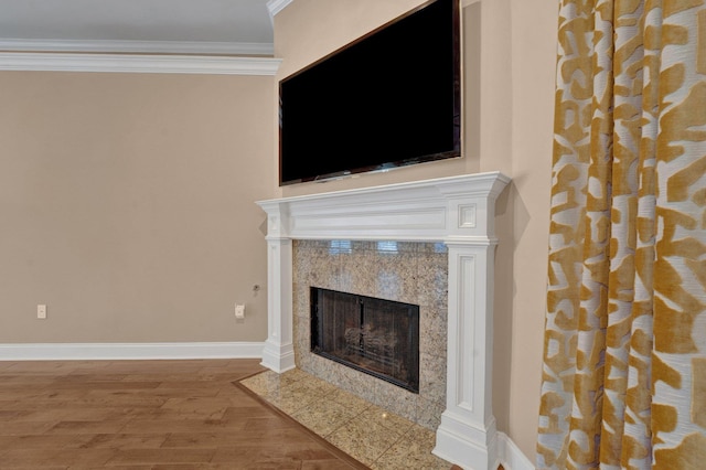 details featuring a fireplace, wood finished floors, crown molding, and baseboards