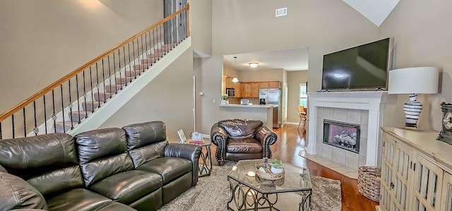 62 Mabel Ln, Atoka, TN 38004 - living room with light wood-style flooring, a high ceiling, a tiled fireplace, and stairway
