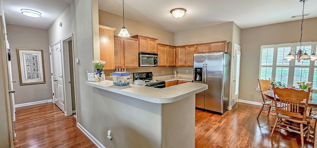 62 Mabel Ln, Atoka, TN 38004 - kitchen featuring stainless steel appliances, light countertops, light wood-style floors, a peninsula, and decorative light fixtures