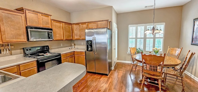 62 Mabel Ln, Atoka, TN 38004 - kitchen with appliances with stainless steel finishes, light wood-style flooring, a chandelier, light countertops, and hanging light fixtures