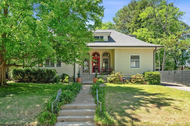 bungalow featuring roof with shingles, a front lawn, and stucco siding
