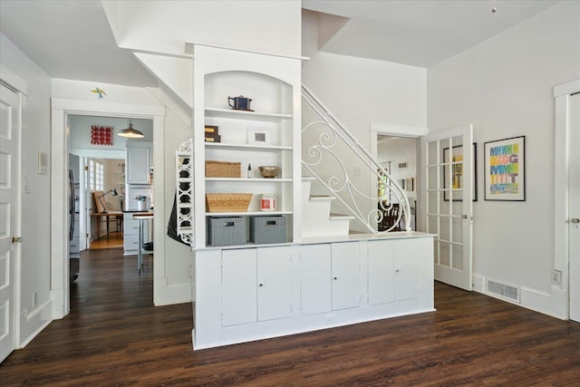 bar with visible vents, black refrigerator, stairs, and dark wood finished floors
