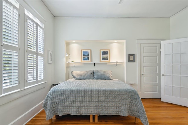 bedroom with multiple windows and wood finished floors