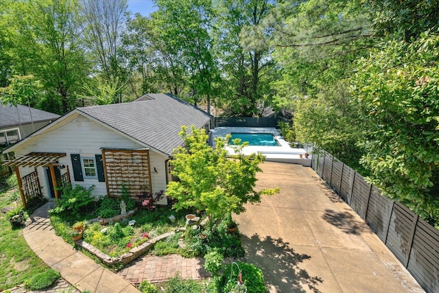 exterior space with a shingled roof, driveway, a fenced backyard, and a fenced in pool