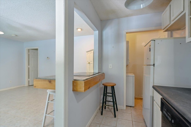 kitchen featuring freestanding refrigerator, a textured ceiling, a kitchen bar, and black dishwasher