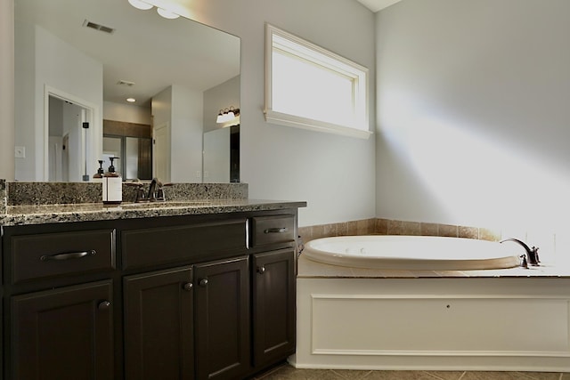 bathroom with a bath, visible vents, and vanity