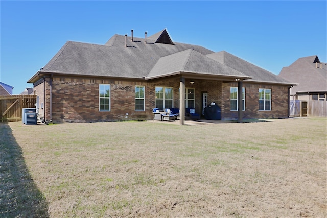 rear view of house featuring brick siding, a yard, and a fenced backyard