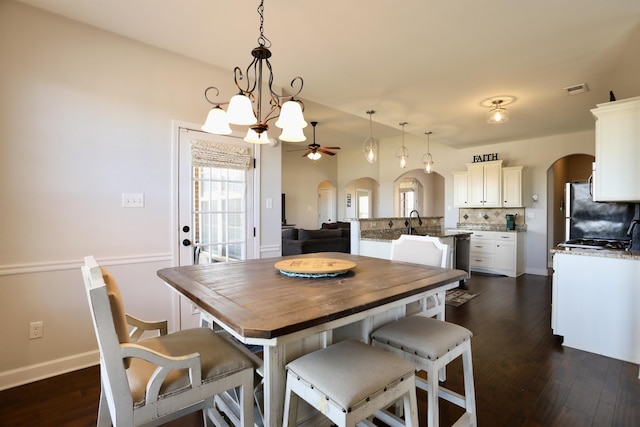 dining room featuring ceiling fan, arched walkways, dark wood-style flooring, and visible vents