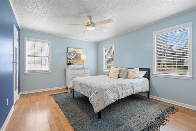 bedroom with a textured ceiling, multiple windows, and light wood-style floors