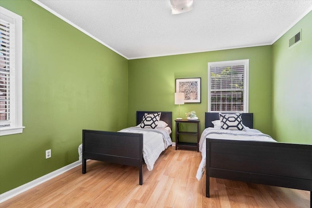 bedroom with ornamental molding, wood finished floors, and visible vents