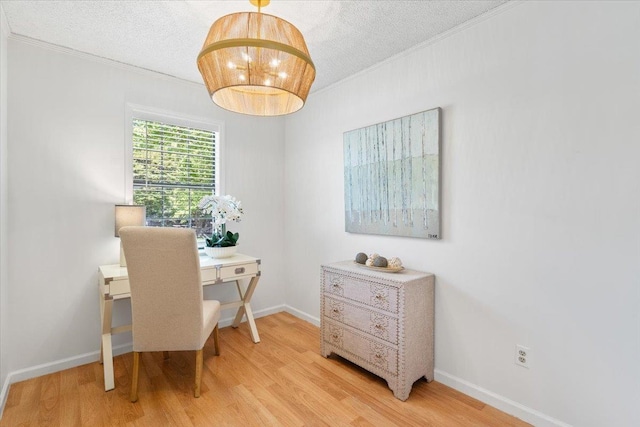 office space with ornamental molding, light wood finished floors, a textured ceiling, and baseboards