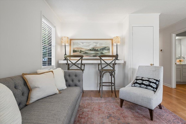 sitting room with ornamental molding and wood finished floors