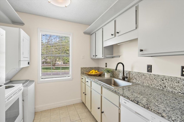 kitchen with a sink, light tile patterned floors, white appliances, baseboards, and a textured ceiling