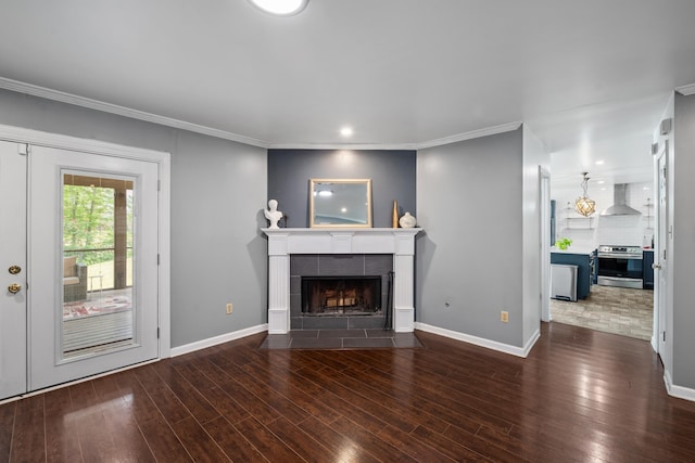 unfurnished living room featuring wood finished floors, a tiled fireplace, baseboards, and recessed lighting