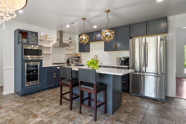 kitchen with stainless steel appliances, backsplash, wall chimney range hood, light countertops, and a kitchen island