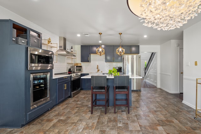kitchen featuring wall chimney range hood, blue cabinets, stainless steel appliances, light countertops, and wine cooler