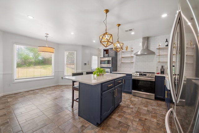 kitchen with blue cabinetry, open shelves, wall chimney range hood, visible vents, and appliances with stainless steel finishes