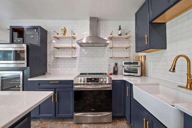kitchen featuring blue cabinets, wall chimney exhaust hood, open shelves, and stainless steel appliances