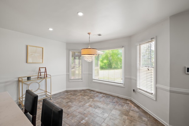 unfurnished dining area with stone finish flooring, baseboards, visible vents, and plenty of natural light