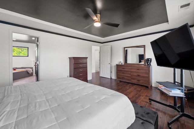 bedroom featuring hardwood / wood-style floors, a tray ceiling, visible vents, ensuite bath, and ceiling fan