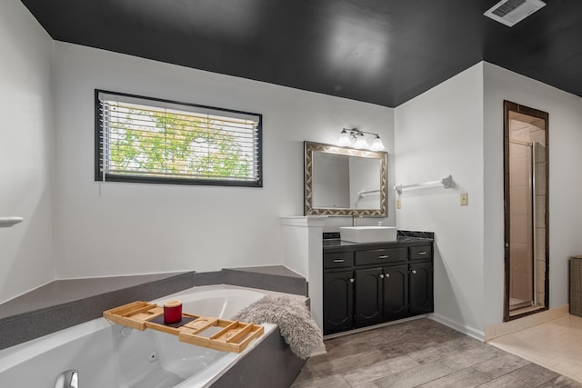 bathroom with vanity, visible vents, a jetted tub, and a shower stall