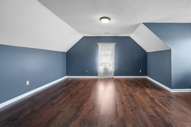 bonus room featuring wood-type flooring, vaulted ceiling, a textured ceiling, and baseboards