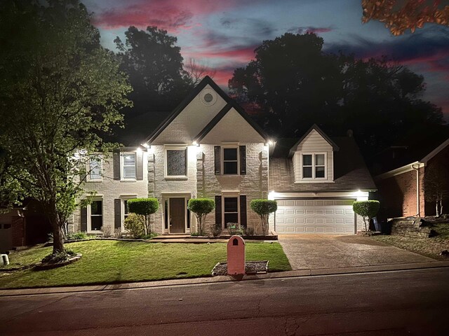 colonial home featuring concrete driveway, an attached garage, and a lawn