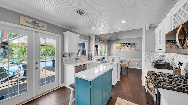 kitchen featuring a peninsula, a sink, visible vents, blue cabinetry, and light countertops