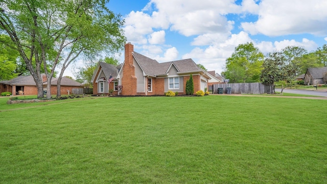 view of front of house with a chimney, fence, a front yard, a garage, and brick siding