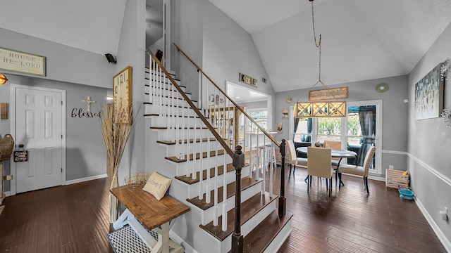 stairs featuring baseboards, wood finished floors, and high vaulted ceiling
