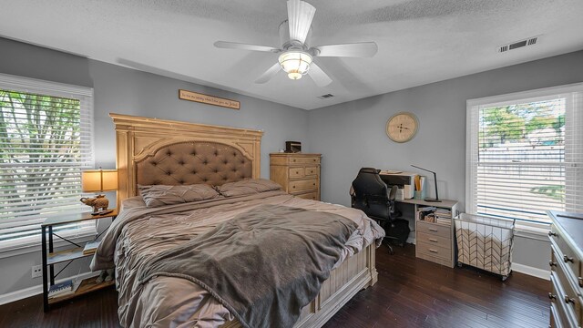 bedroom with dark wood-style flooring, visible vents, and multiple windows