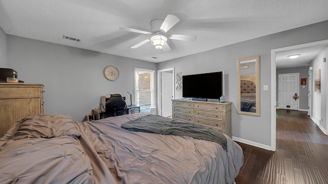 bedroom featuring baseboards, visible vents, a textured ceiling, and dark wood-style floors