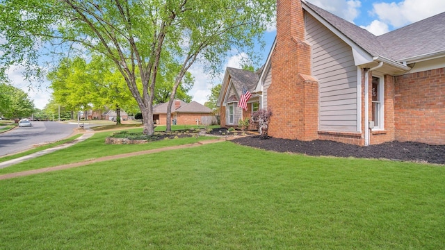 view of home's exterior featuring a lawn, roof with shingles, brick siding, and a chimney