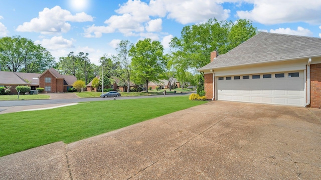 view of yard featuring driveway, a residential view, and a garage