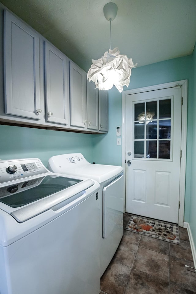 washroom with cabinet space, baseboards, a notable chandelier, and washer and clothes dryer