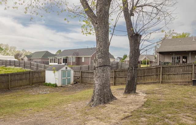 view of yard featuring a fenced backyard, an outdoor structure, a residential view, and a storage unit