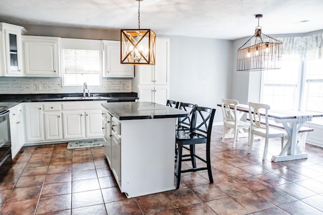 kitchen with decorative backsplash, dark countertops, a breakfast bar, and a kitchen island
