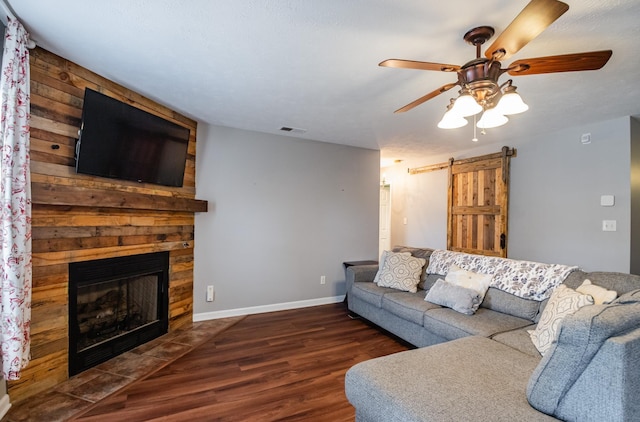 living room featuring a barn door, wood finished floors, visible vents, baseboards, and a fireplace