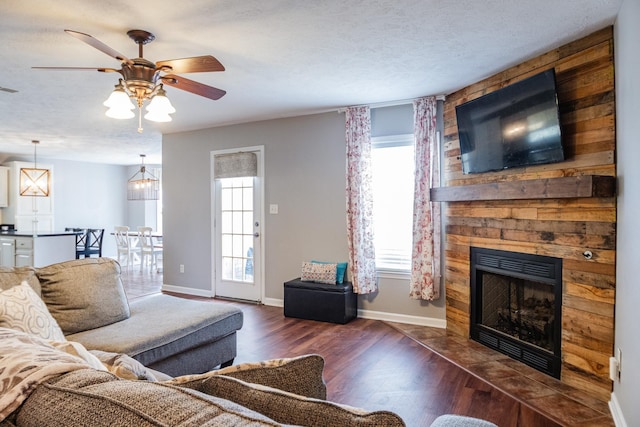 living room featuring wood finished floors, visible vents, a ceiling fan, baseboards, and a fireplace