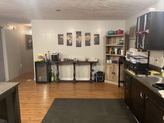 kitchen with wood finished floors, a textured ceiling, and a sink