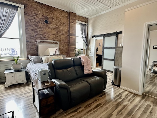 132 W Court Ave, Selmer, TN 38375 - bedroom with crown molding, brick wall, wood finished floors, and a barn door