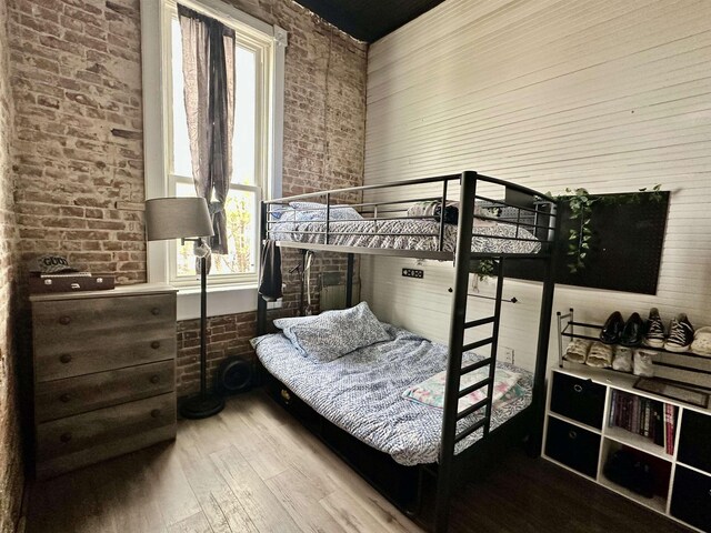 132 W Court Ave, Selmer, TN 38375 - bedroom featuring brick wall, wood-type flooring, and multiple windows