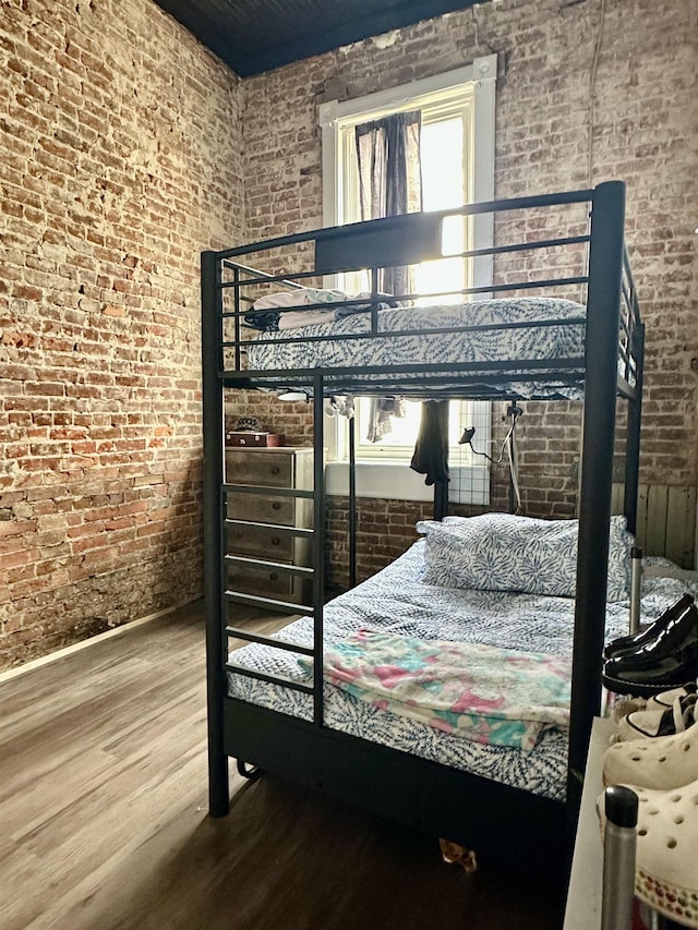 132 W Court Ave, Selmer, TN 38375 - bedroom with brick wall, baseboards, and wood finished floors