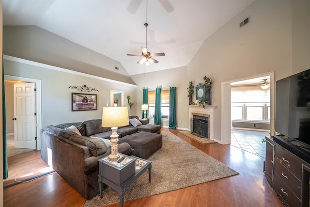 living area featuring a tile fireplace, wood finished floors, high vaulted ceiling, and ceiling fan