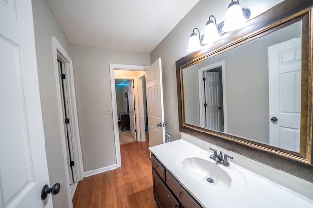 bathroom featuring baseboards, vanity, wood finished floors, and a textured ceiling
