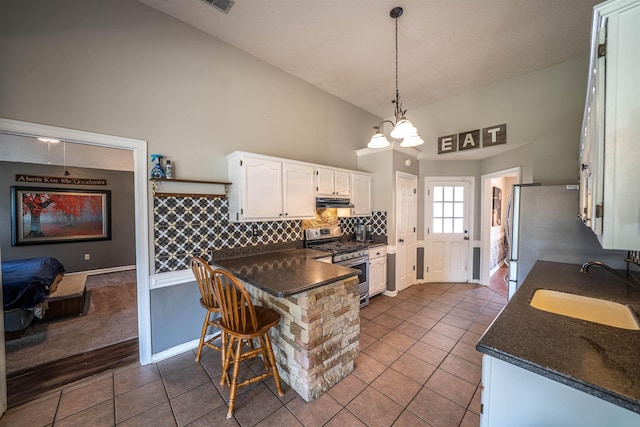 kitchen with stainless steel appliances, a sink, dark countertops, white cabinetry, and dark tile patterned flooring