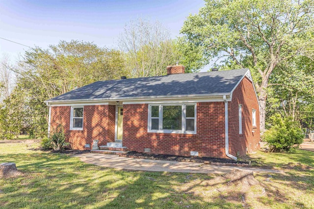 view of front of home with brick siding, a chimney, a front yard, and crawl space